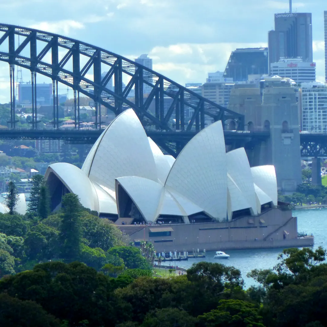 Sydney Opera House and Harbour Bridge above the harbour and trees